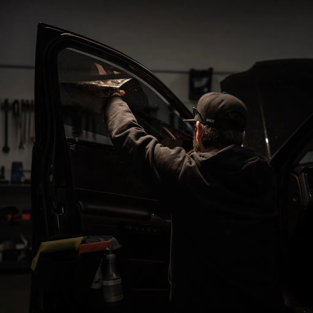 Technician applying professional window tint to a vehicle at Darkmode Window Tint