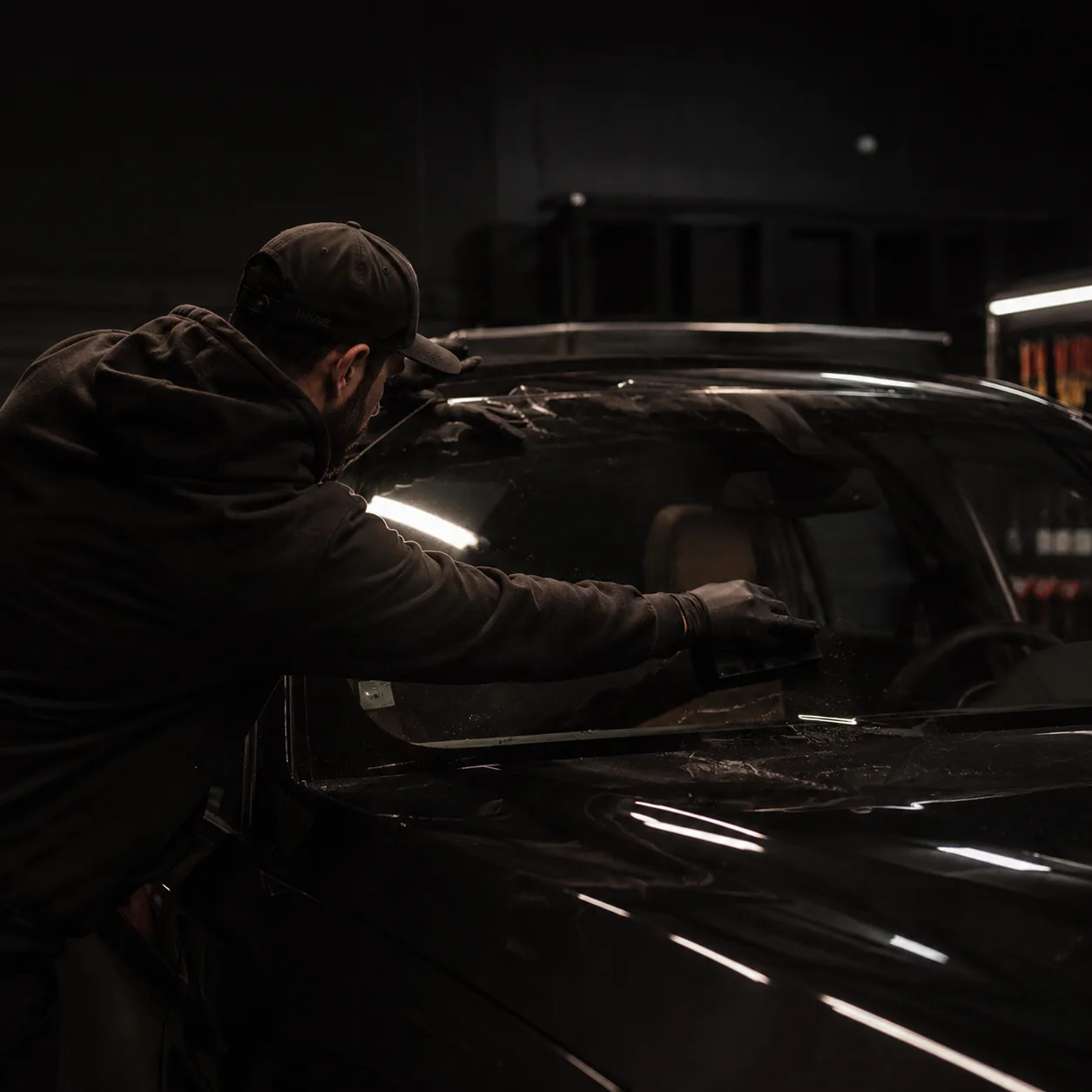 Technician applying professional window tint to a vehicle windshield